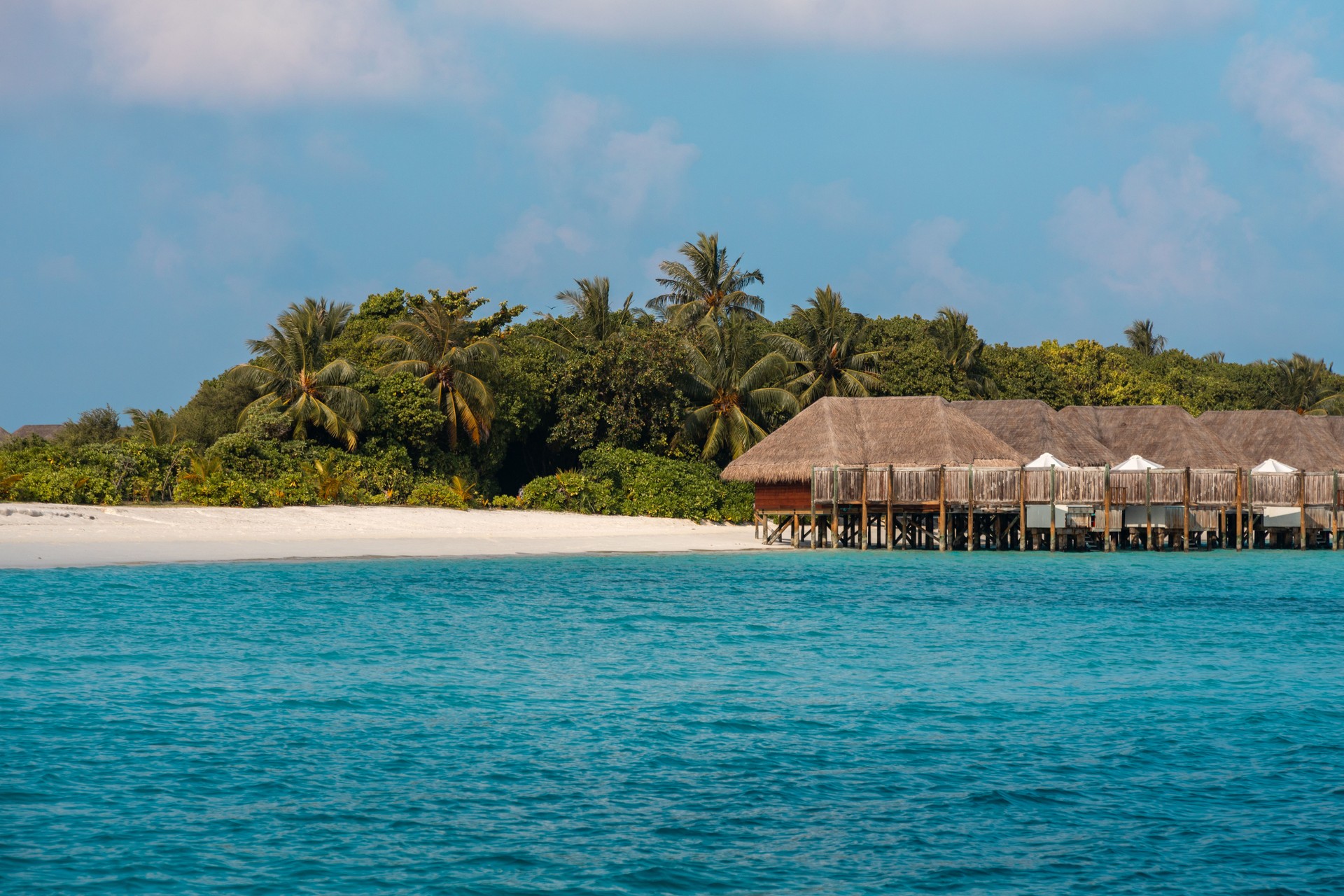 luxury overwater villa bungalows in Maldives island resort with wood jetty in turquoise lagoon  on sunny vacation day in tropical hotel